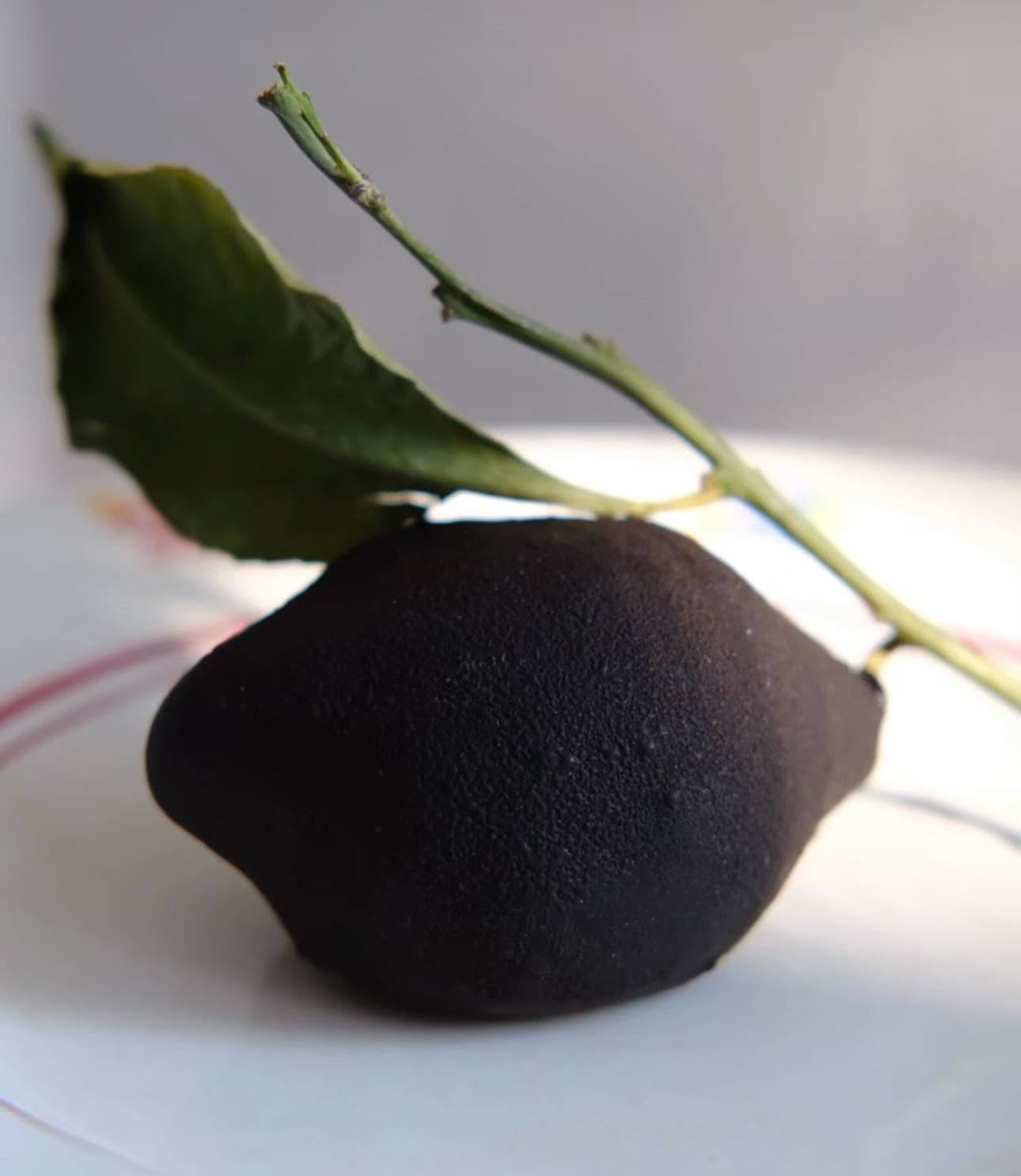 Lemon-shaped dessert coated in dark chocolate, with a lemon leaf