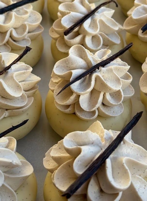 Raspberry and vanilla pastries topped with piped cream and a vanilla pod